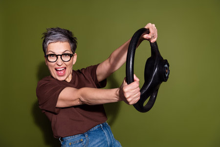 Portrait of pretty aged lady hold wheel wear brown t-shirt isolated on khaki color background