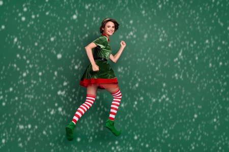Photo of energetic lady jump hurry wear elf costume hat striped socks isolated green color backgroundの写真素材