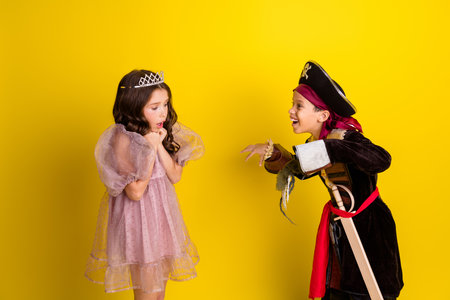 Portrait of two little kids halloween princess pirate costume dead scary arm isolated on yellow color backgroundの写真素材