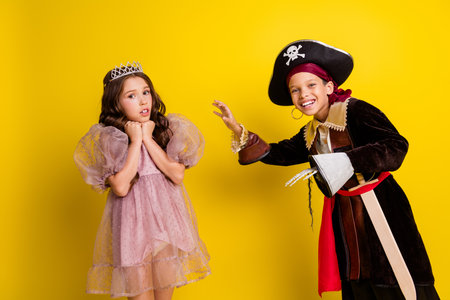 Portrait of two kids halloween princess pirate costume tell frightening story isolated on yellow color backgroundの写真素材