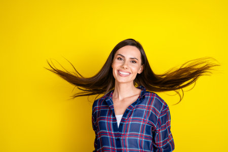 Photo portrait of pretty young girl shampoo fluttering hair wear trendy plaid outfit isolated on yellow color backgroundの写真素材