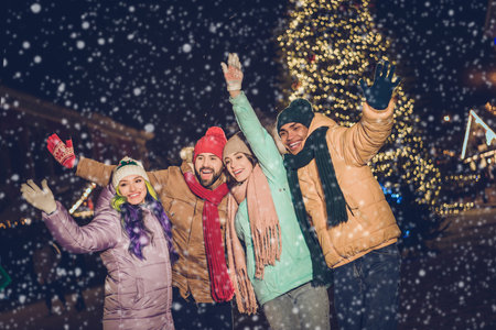 Portrait of group funny excited buddies arms waving hi have good mood x-mas evening lights outdoors