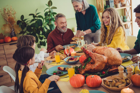 Photo of charming happy big family celebrating thanksgiving day cosy october sitting eating turkey indoors room homeの写真素材