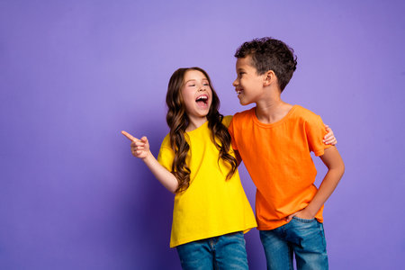 Photo of charming two little children laughing point empty space wear trendy orange yellow outfit...