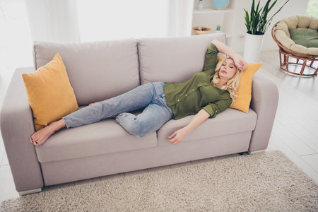Photo of cute adorable woman lying on divan suffering migraine weekend at home relax rest living room indoorsの写真素材