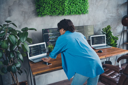 Photo of pretty young girl standing work coding laptop monitors wear blue shirt coworking programmer...
