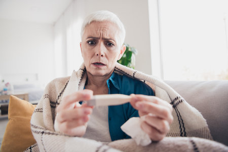 Portrait of nice aged woman hold thermometer wear blue shirt bright interior flat indoors