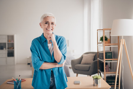 Photo of nice retired female thinking touch chin wear blue clothes enjoy modern cozy interior flat indoorsの写真素材