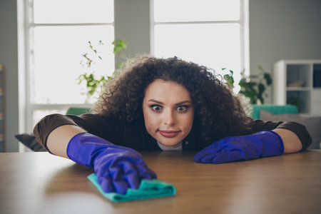 Closeup photo of attractive housewife young woman single using rag cleaning table surface indoors comfortable loft apartmentの写真素材
