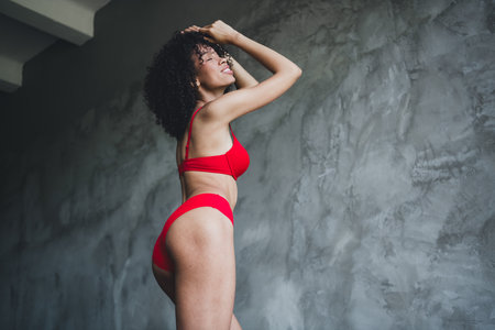 Photo of attractive young girl posing show booty touch head wear red fashion lingerie isolated concrete wall background no filterの写真素材