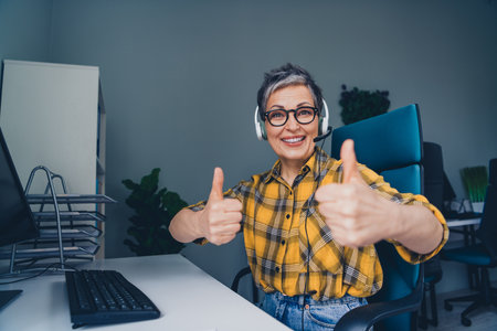 Photo of lovely pensioner lady thumb up support manager wear plaid yellow shirt coworking successful nice light officeの写真素材
