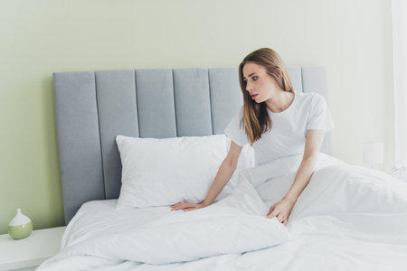 Photo of unhappy upset lady dressed sleepwear feeling loneliness sitting bed indoors room home houseの写真素材