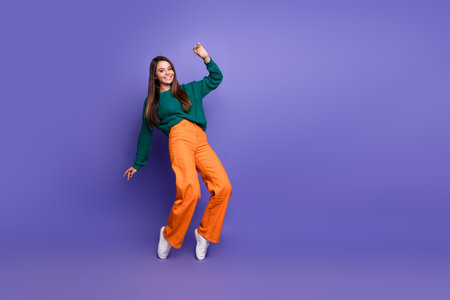 Full body portrait of pretty young girl dancing empty space isolated on violet color backgroundの写真素材