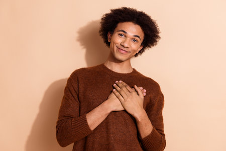 Cheerful young african american male student in casual outfit posing with a smile against a beige backgroundの写真素材