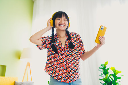 Photo of pretty young woman smart phone headphones wear shirt weekend modern interior apartment indoorsの写真素材