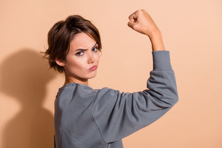 Photo portrait of pretty young girl serious face raise eyebrow show muscle wear trendy gray outfit...