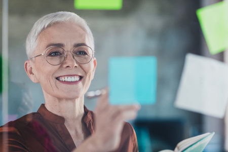 Photo of senior businesswoman stickers ideas cheerful smile wear brown shirt executive business leader modern office interior workspaceの写真素材