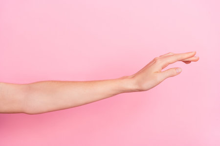 Cropped close up photo of woman hand raise touch empty space isolated on pink color backgroundの写真素材
