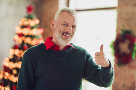 Portrait of nice aged man demonstrate thumb up wear sweater new year xmas holiday flat indoors