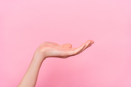 Cropped close up portrait of girl arm palm demonstrate hold empty space isolated on pink color backgroundの写真素材