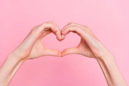 Cropped close up photo of girl hands fingers make heart healthcare symbol isolated on pink color backgroundの写真素材