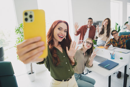 Photo of cheerful friendly young it coworkers enjoying education together recording video modern device indoors workplace workshopの写真素材