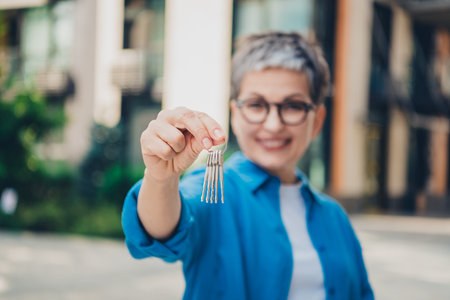 Blurred photo of nice aged lady arm hold keys wear blue shirt downtown street city outdoorsの写真素材