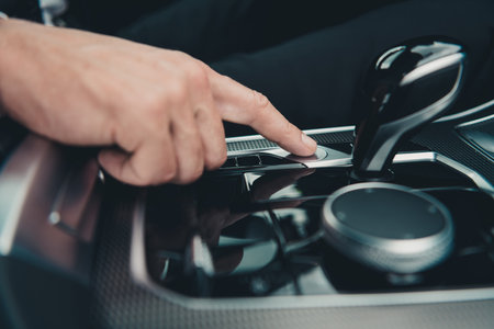 Close-up of a hand pressing a button in a car interior, showing modern technology and driving controlsの写真素材