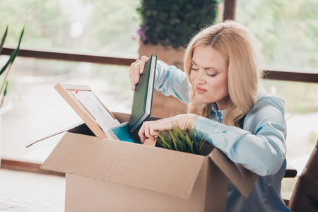 Portrait of young business woman unsatisfied packing box fired loft interior business center office...