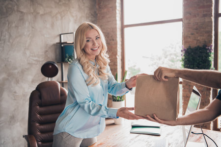 Photo of successful corporate worker lady receive food delivery courier modern loft interior office indoorsの写真素材