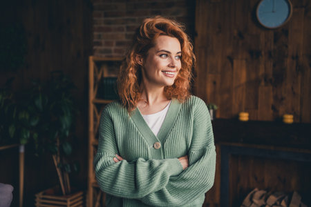 Photo of shiny cute woman dressed green cardigan smiling arms folded indoors house apartment roomの写真素材