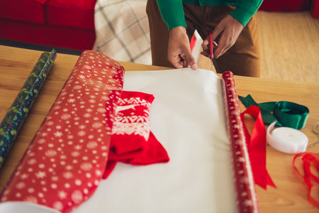 Cropped photo of guy arms dressed green pullover wrapping x-mas gifts indoors house apartment room