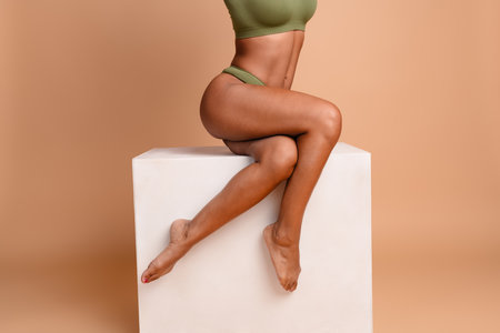 Studio cropped no retouch photo of sexy lady dressed lingerie sitting white podium blank space isolated ivory color backgroundの写真素材