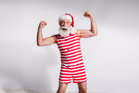 Photo of cheerful optimistic santa claus wear striped costume raise hands fists isolated on white color backgroundの写真素材