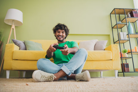 Full size photo of nice young man enjoy play games wear t-shirt modern green interior apartment...
