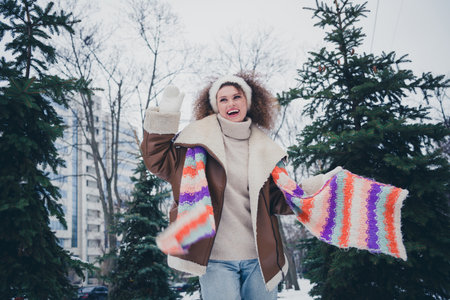 Photo of pretty young woman throw scarf wave hi wear jacket walk snowy street weekend outdoors