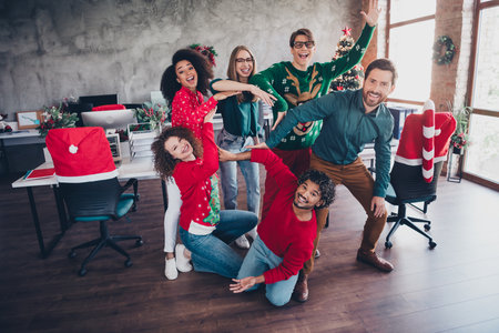 Full body photo of cheerful young people colleagues posing team show circle cozy christmas party decor spacious office indoorsの写真素材