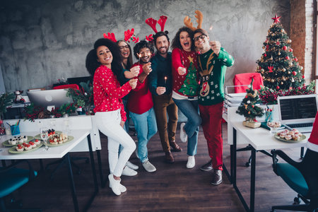Full length photo of attractive young people employees hold bengal lights new year decoration interior corporate party officeの写真素材