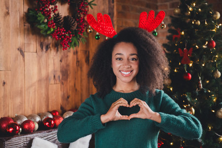 Photo of lovely attractive girl wear green sweater enjoy xmas festive event new year magic heart love indoors home roomの写真素材