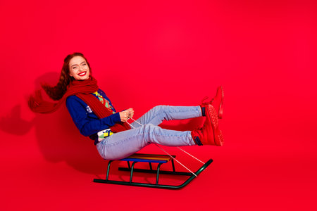 Full size photo of pretty young girl ride sledge wear trendy blue christmas outfit masquerade theme party on red color backgroundの写真素材