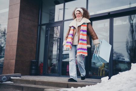 Full body portrait of nice young girl hold mall bags outerwear walk snowy weather city street outdoors