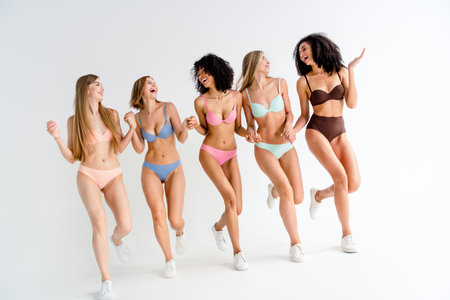 Full body photo no filter of pretty girls posing body positive hold hands walk wear colorful lingerie natural day light studio backgroundの写真素材