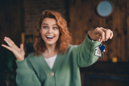Photo of impressed cheerful lady wear green cardigan showing you keys indoors room home houseの写真素材