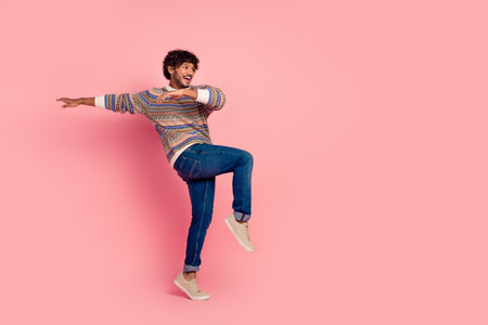 Full body portrait of nice young man dance empty space ad wear sweater isolated on pink color...