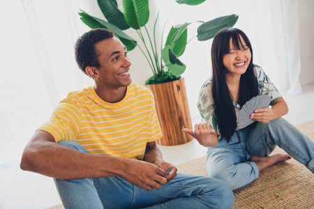 Photo of good mood cheerful couple wife and husband sit floor play poker game cards indoors apartmentの写真素材