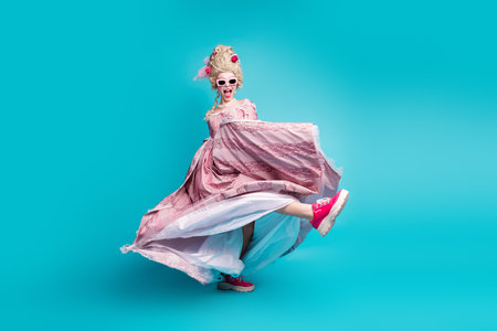 Full size portrait of young princess girl hold vintage dress dance footwear ad isolated on turquoise color backgroundの写真素材
