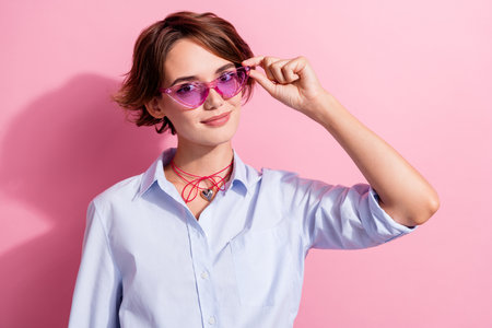 Photo of stunning satisfied young person hand touch cool sunglass ad isolated on pink color backgroundの写真素材