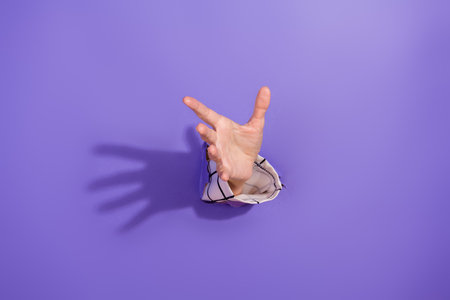 Creative concept of a human hand reaching out through a purple background symbolizing opportunity, assistance and connectionの写真素材