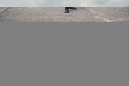 Senior businessman standing confidently with bag near luxury car in city parking lot during a phone callの写真素材