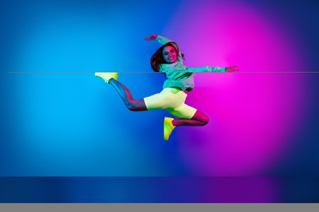 Full length photo of charming positive woman wear green sweatshirt dancing jumping high isolated neon blue color backgroundの写真素材